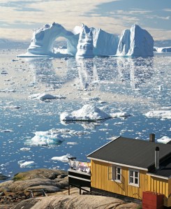 Greenland, Disko Bay, Ilulissat, wooden house with large iceberg in background